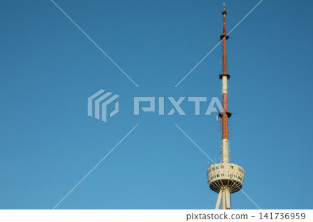 Tall communications tower stands against expansive blue sky Tall communications tower stands against expansive blue sky 141736959