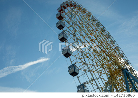Ferris wheel captivates visitors at amusement park under bright sky Ferris wheel captivates visitors at amusement park under bright sky 141736960
