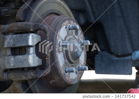 Close-up of a rusty car brake rotor and caliper assembly with wheel studs Close-up of a rusty car brake rotor and caliper assembly with wheel studs 141737542