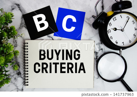 BC Buying Criteria text written on notepad with alarm clock and magnifying glass on marble background BC Buying Criteria text written on notepad with alarm clock and magnifying glass on marble background 141737963
