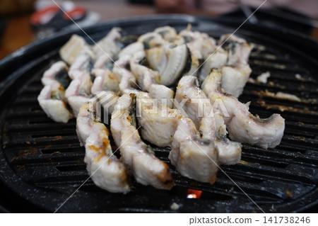 Fresh eels grilling on a charcoal brazier grill close up Fresh eels grilling on a charcoal brazier grill close up 141738246