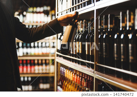 Sommelier Selecting Fine Wine Bottle From Cellar Collection While Consulting Description 141740472