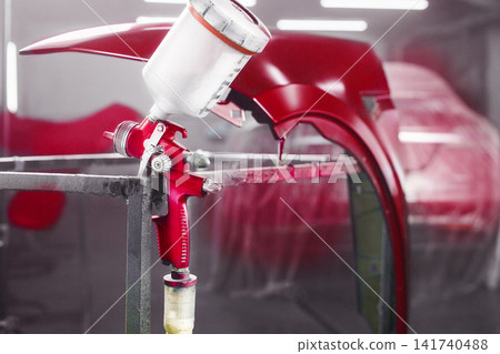 Airbrush gun in paint chamber on painted part car background. Painting of car body part in chamber with use airbrush gun. Airbrush gun in paint chamber on painted part car background. Painting of car body part in chamber with use airbrush gun. 141740488