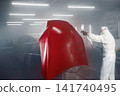 Professional car painter in chamber paints automobile bonnet. 141740495