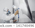 Car repairman painter in mask and protective workwear priming car before painting in paint chamber. 141740496
