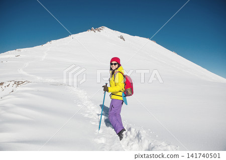 Smiling Woman Ascending Mountain Peak With Trekking Poles Against Clear Blue Sky Smiling Woman Ascending Mountain Peak With Trekking Poles Against Clear Blue Sky 141740501