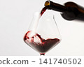 Red wine pouring into tilted wineglass from bottle. 141740502