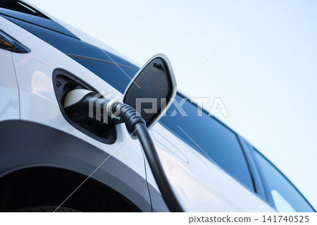 Electric car charging at a outdoor public charging station. Electric car charging at a outdoor public charging station. 141740525