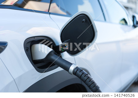 Electric car charging at a outdoor public charging station. Electric car charging at a outdoor public charging station. 141740526