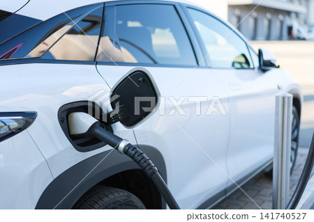 Electric car charging at a outdoor public charging station. Electric car charging at a outdoor public charging station. 141740527