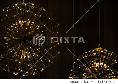 Warm LED starburst chandeliers hang against a dark wood background Warm LED starburst chandeliers hang against a dark wood background 141740610
