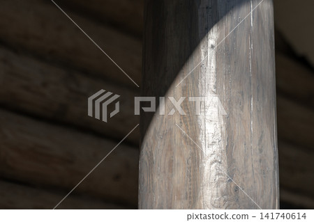 Sunlight falls across a hand-hewn wooden post inside a rustic cabin Sunlight falls across a hand-hewn wooden post inside a rustic cabin 141740614