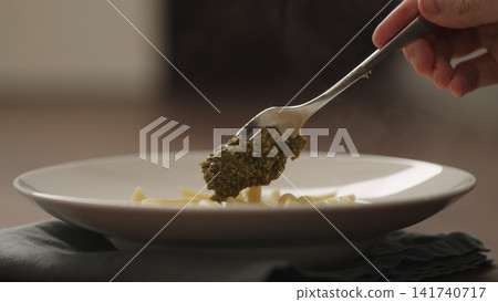 Slow motion making pesto penne pasta with mozzarella and tomatoes in deep plate closeup Slow motion making pesto penne pasta with mozzarella and tomatoes in deep plate closeup 141740717