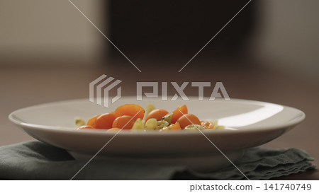 making pesto penne pasta with mozzarella and tomatoes in deep plate closeup making pesto penne pasta with mozzarella and tomatoes in deep plate closeup 141740749