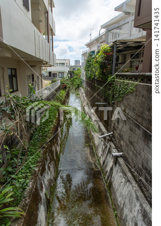 A well-maintained, narrow river that runs through a residential area. A well-maintained, narrow river that runs through a residential area. 141741435