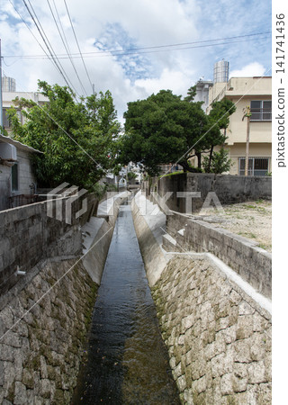 A well-maintained, narrow river that runs through a residential area. A well-maintained, narrow river that runs through a residential area. 141741436