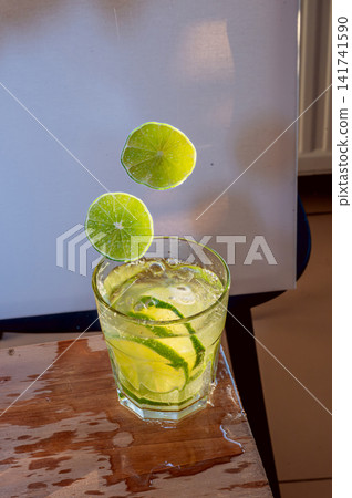 Lime Above a Glass of Refreshing Drink Lime Above a Glass of Refreshing Drink 141741590