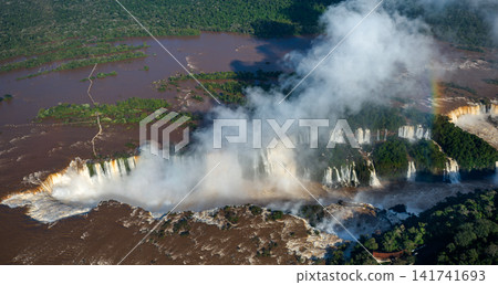 An aerial panorama capturing the Iguazu Falls, which spread out beneath a massive plume of mist. An aerial panorama capturing the Iguazu Falls, which spread out beneath a massive plume of mist. 141741693