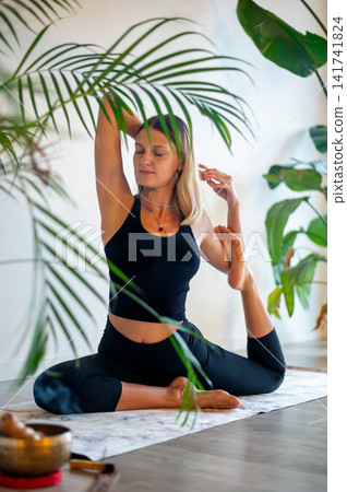 Woman in a Seated Side Stretch Among House Plants Woman in a Seated Side Stretch Among House Plants 141741824