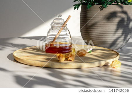 Drizzling Honey into a Jar Beside Chrysanthemums Drizzling Honey into a Jar Beside Chrysanthemums 141742096
