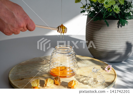 Hand Drizzling Honey into a Glass Beehive Jar Hand Drizzling Honey into a Glass Beehive Jar 141742201