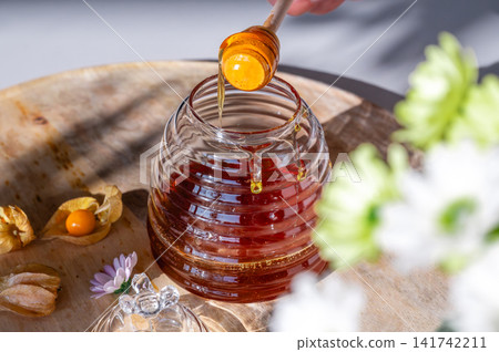 Honey Jar and Dipper with Flowers on a Board 141742211