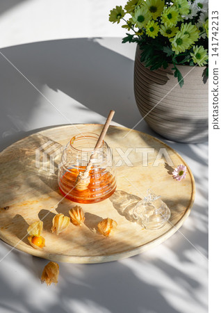 Honey Jar with Wooden Dipper and Summer Flowers 141742213