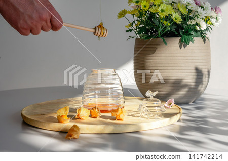 Hand Pouring Honey into a Beehive Shaped Jar Hand Pouring Honey into a Beehive Shaped Jar 141742214