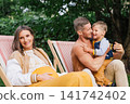 Pregnant Mother Smiling While Father Plays With Son 141742402