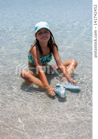 Little Girl Playing in the Shallow Sea on a Beach Little Girl Playing in the Shallow Sea on a Beach 141742452