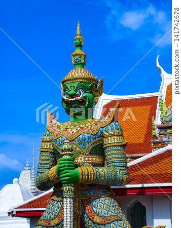 Colorful giant guardian statue at Wat Phra Kaew with traditional Thai temple architecture in Bangkok. Colorful giant guardian statue at Wat Phra Kaew with traditional Thai temple architecture in Bangkok. 141742678
