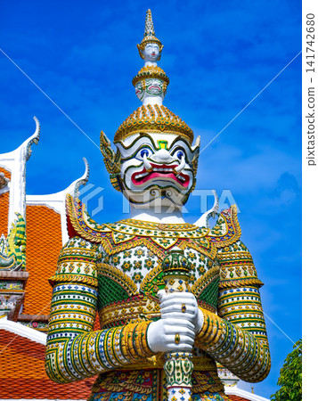 Colorful giant guardian statue at Wat Phra Kaew with traditional Thai temple architecture in Bangkok. Colorful giant guardian statue at Wat Phra Kaew with traditional Thai temple architecture in Bangkok. 141742680