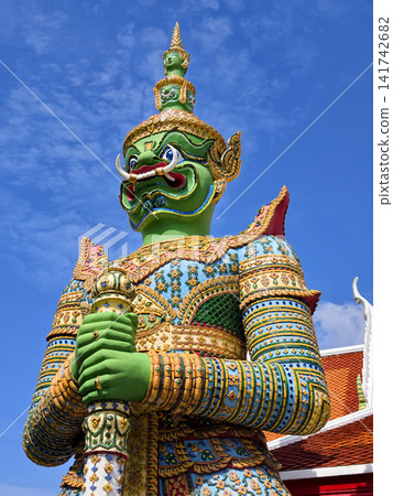 Colorful giant guardian statue at Wat Phra Kaew with traditional Thai temple architecture in Bangkok. Colorful giant guardian statue at Wat Phra Kaew with traditional Thai temple architecture in Bangkok. 141742682