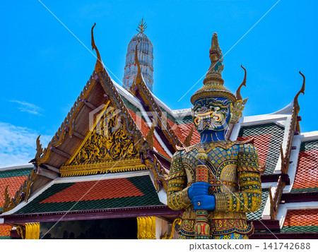 Colorful giant guardian statue at Wat Phra Kaew with traditional Thai temple architecture in Bangkok. Colorful giant guardian statue at Wat Phra Kaew with traditional Thai temple architecture in Bangkok. 141742688