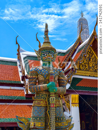 Colorful giant guardian statue at Wat Phra Kaew with traditional Thai temple architecture in Bangkok. Colorful giant guardian statue at Wat Phra Kaew with traditional Thai temple architecture in Bangkok. 141742691