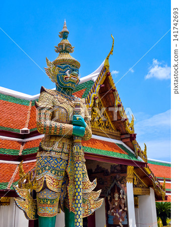 Colorful giant guardian statue at Wat Phra Kaew with traditional Thai temple architecture in Bangkok. Colorful giant guardian statue at Wat Phra Kaew with traditional Thai temple architecture in Bangkok. 141742693