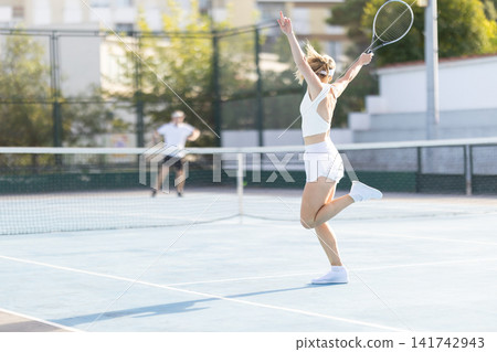 Tennis players practice on a sunny day at an outdoor court in a city Tennis players practice on a sunny day at an outdoor court in a city 141742943