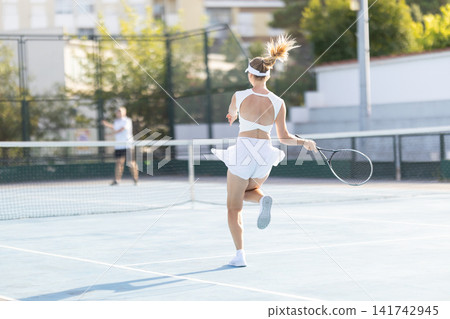 Tennis match shows a player serving on a sunny day at the local sports court Tennis match shows a player serving on a sunny day at the local sports court 141742945