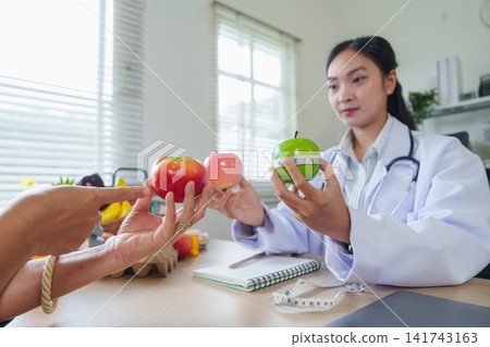 Asian female nutritionist consulting patient about healthy diet and fruit nutrition in clinic Asian female nutritionist consulting patient about healthy diet and fruit nutrition in clinic 141743163