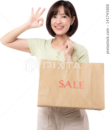 Happy asian woman holding paper bag making okay sign gesture showing cheerful smile during discount shopping sale period transparency Happy asian woman holding paper bag making okay sign gesture showing cheerful smile during discount shopping sale period transparency 141743808