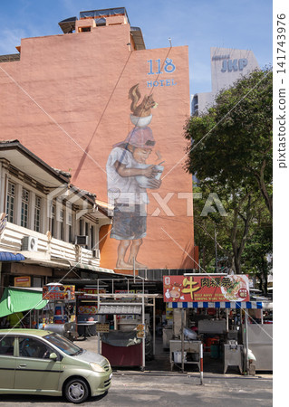 Penang, Malaysia - May 17, 2024: Colorful street mural depicting a boy holding a smartphone while standing on a man's shoulders, showcasing urban art in a vibrant city environment Penang, Malaysia - May 17, 2024: Colorful street mural depicting a boy holding a smartphone while standing on a man's shoulders, showcasing urban art in a vibrant city environment 141743976