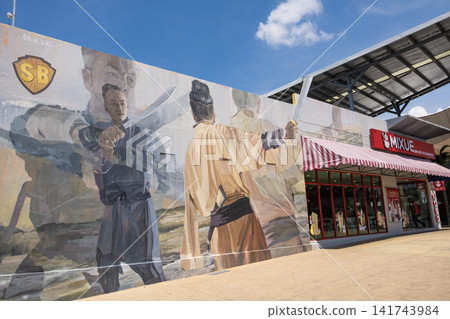 Colorful mural depicting two warriors in combat, showcasing dynamic poses and intricate details, set against a bright blue sky and urban environment with storefronts nearby Colorful mural depicting two warriors in combat, showcasing dynamic poses and intricate details, set against a bright blue sky and urban environment with storefronts nearby 141743984