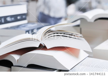 stack of books, close up. Open book on the table in library. Back to school concept. Open book on table with blur bookshelf background stack of books, close up. Open book on the table in library. Back to school concept. Open book on table with blur bookshelf background 141744111