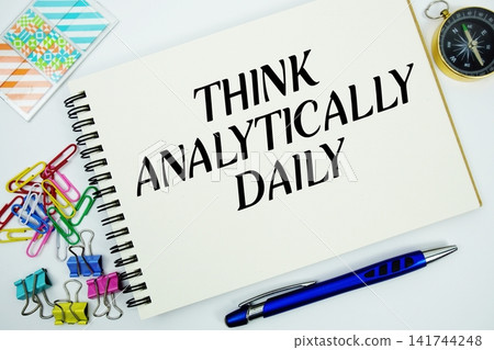 Think Analytically Daily text message written on notepad with stationery flat lay on white background Think Analytically Daily text message written on notepad with stationery flat lay on white background 141744248