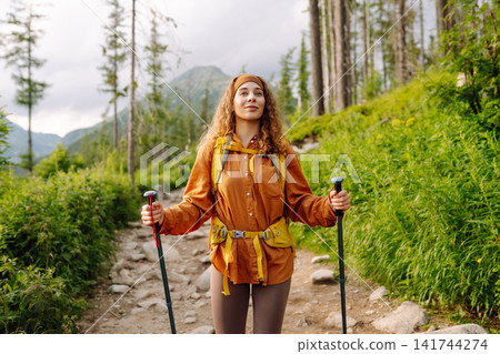 Woman travels along hiking trails among mountains with yellow backpack and hiking boots. Vacation. Woman travels along hiking trails among mountains with yellow backpack and hiking boots. Vacation. 141744274