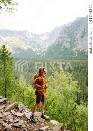 Smiling traveler with a bright backpack on a hiking mountain trail. Active lifestyle. Smiling traveler with a bright backpack on a hiking mountain trail. Active lifestyle. 141744293