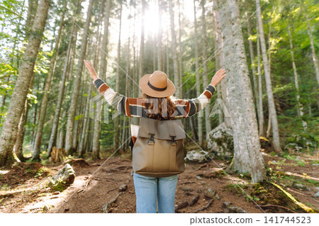 Woman with backpack hiking outdoors in the Forest. Trekking in the Pine Woods. Hiking lifestyle Woman with backpack hiking outdoors in the Forest. Trekking in the Pine Woods. Hiking lifestyle 141744523