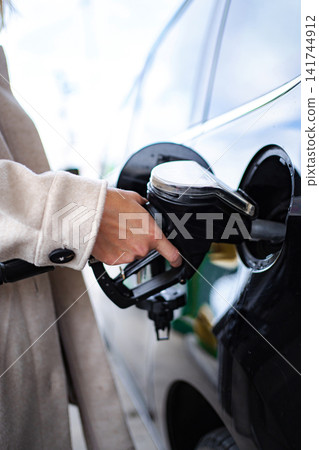 Woman hand fueling black car at gas station Woman hand fueling black car at gas station 141744912