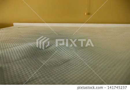 Close-up view of a worn, stained mattress surface with a checkered pattern and signs of aging, home hygiene, cleaning, and damage concept Close-up view of a worn, stained mattress surface with a checkered pattern and signs of aging, home hygiene, cleaning, and damage concept 141745237