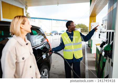 Gas station attendant assisting customer refueling vehicle Gas station attendant assisting customer refueling vehicle 141745418